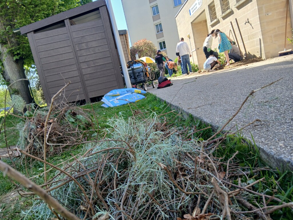 Participants nettoient un jardin, avec un abri et des outils, pendant une activité de loisirs communautaire.