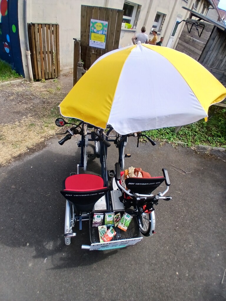 Vélos adaptés aux PMR avec parapluie, présentés par Roulez JEUnesse Loisirs, avec panier rempli de produits.