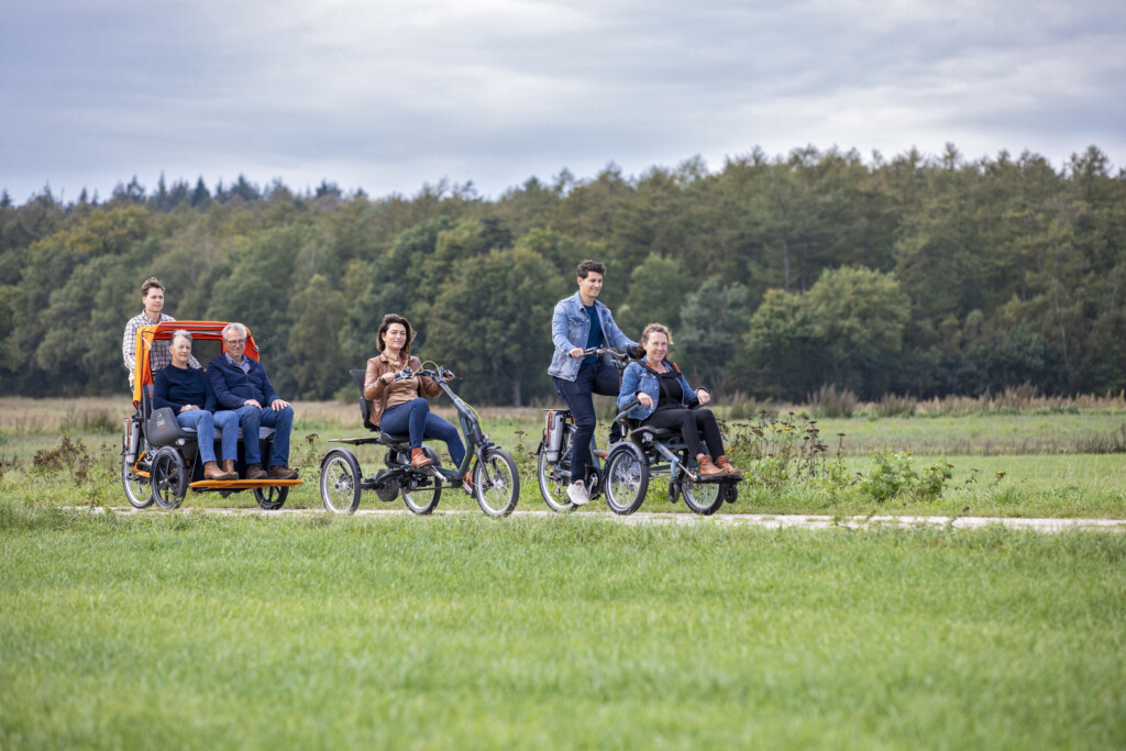 Groupe de personnes à vélo, incluant un vélo adapté pour seniors et un cycliste en VAE, sur un chemin en pleine nature.