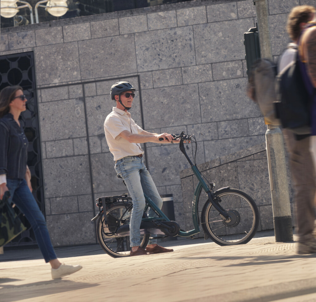 Homme à vélo électrique dans une rue, entouré de piétons, mettant en avant les options de mobilité de Roulez JEUnesse Loisirs.