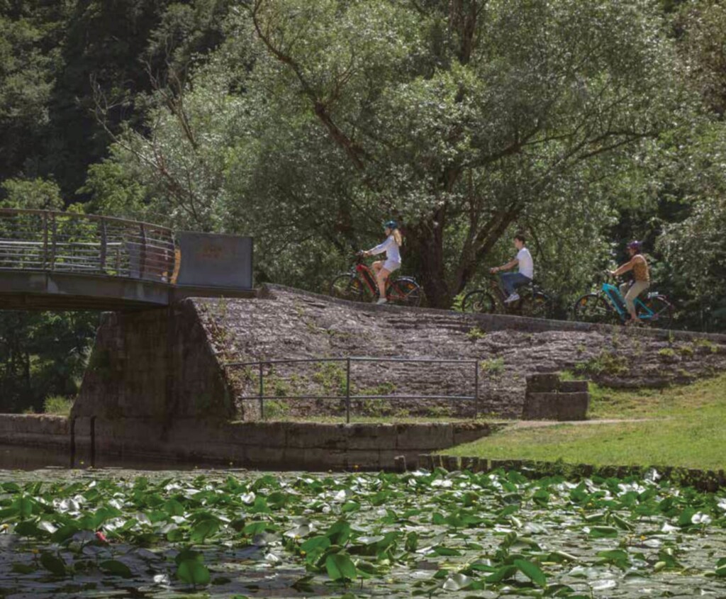 Trois cyclistes sur un chemin naturel, avec le logo et le titre du catalogue VIRAGE en bas.