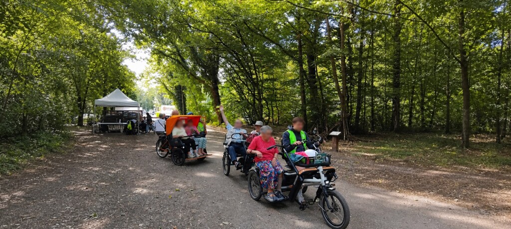 Groupe de personnes à bord de vélos adaptés, profitant d'une balade en plein air sur un chemin forestier.